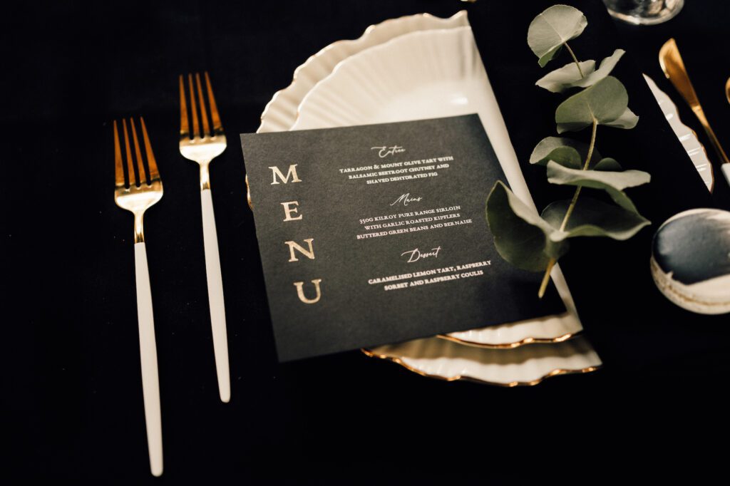 Black and gold wedding menu on white charger plate